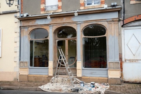 A wooden shop front stripped back and primed for repair